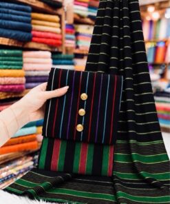 An overview of the unstitched set PR-142 by Abu Hurairah Fabrics, featuring folded check-style fabric for the shirt, trouser, and dupatta, accessorized with old brass measuring tape on dark wood.